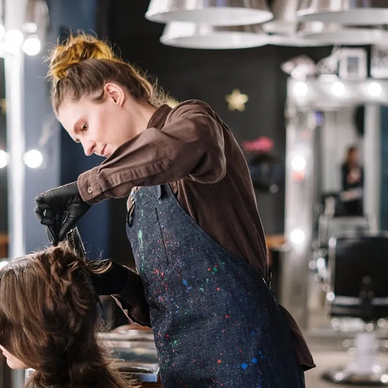 A stylist working on a client at the salon chair